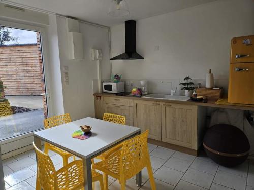 una cucina con tavolo e sedie e una cucina con bancone di L'Ecrin - L'Améthyste a Châteaubriant