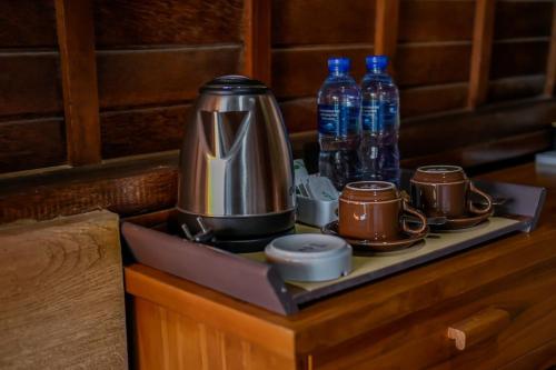 - une cafetière sur un plateau avec des tasses et des bouteilles d'eau dans l'établissement Abing Dalem - Villa Mangga, à Tabanan