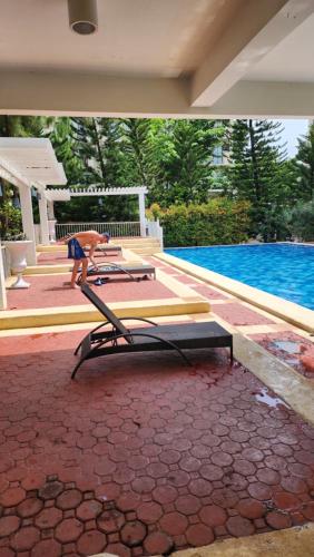 a person standing next to a table next to a pool at 2BR NORTHPOINT CONDO Free Airport Pick up for 3 nights stay or more in Davao City