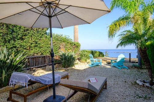 a patio with an umbrella and chairs and the ocean at Kyma II Beachfront Residence in Polis Chrysochous