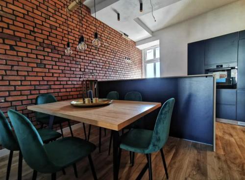 a dining room with a wooden table and green chairs at Kolejowa 4 Boutique Apartment in Nowa Ruda