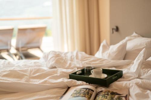 bandeja con una taza y un libro en la cama en Pergola Residence, en Lagundo