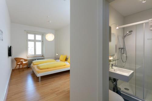 a bedroom with a bed and a sink and a shower at Pensionsieben Das andere Hotel in Lörrach