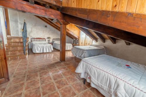 a attic room with three beds and a staircase at Casa Rural Castillo Diempures in Cantalojas