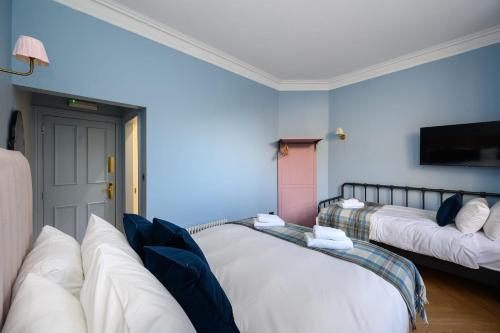 a room with two beds and a flat screen tv at Queen Charlotte Guesthouse in Edinburgh
