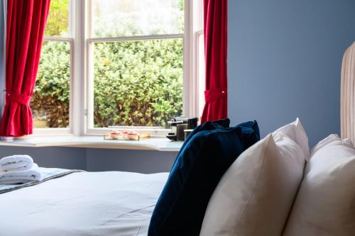 a bedroom with a bed with red curtains and a window at Queen Charlotte Guesthouse in Edinburgh