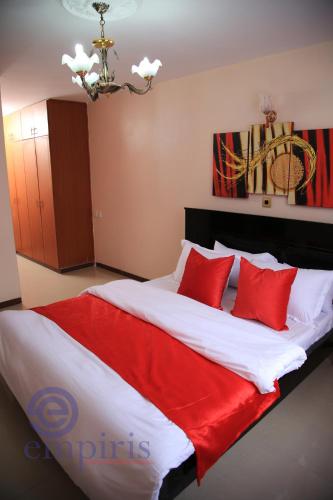 a bedroom with a large bed with red pillows at 1BR Luxury Apartment Milimani Nakuru, Empiris with Pool, Gym, Near Golf Club in Nakuru