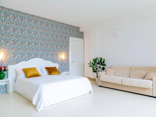 a white bedroom with a bed and a couch at Relais San Martino Salento - Handwritten Collection in Taviano