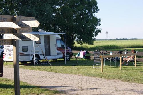 un letrero de la calle junto a una caravana y una tienda de campaña en Camping de Noorde, en Zwartsluis
