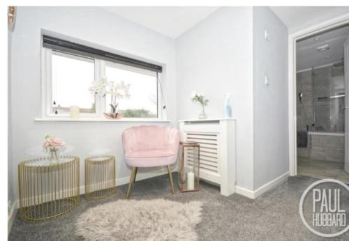邦吉的住宿－Immaculate 3-Bed House in Bungay，客厅配有粉红色的椅子和窗户