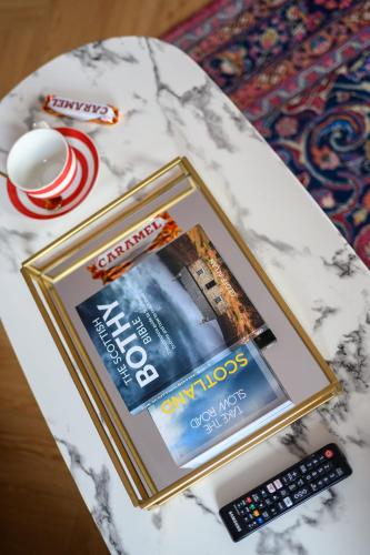 a table with a book and a remote control at Queen Charlotte Guesthouse in Edinburgh