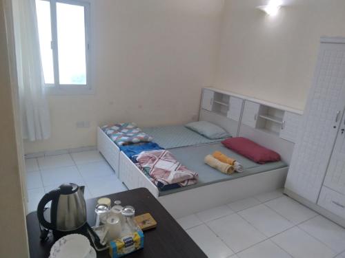 Habitación pequeña con 2 camas y mesa. en Daily stay Royal flat, en Dubái