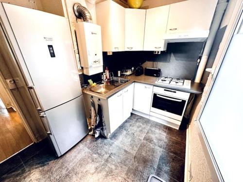 a small kitchen with white cabinets and a refrigerator at Appartement 2 pièces in Malakoff