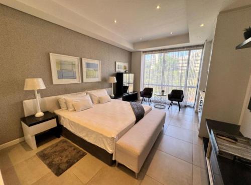 a bedroom with a large bed and a living room at Love Luxe @ Sandton skye in Johannesburg