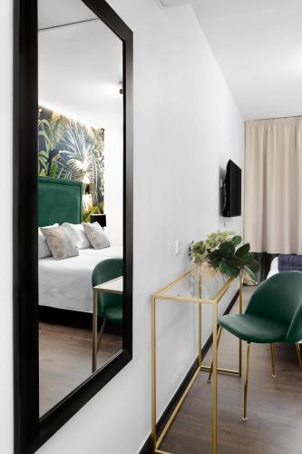 a mirror in a room with a bed and a chair at Hotel Los Girasoles by Maxi Hoteles in Granada