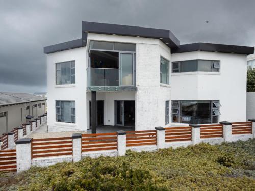a white house with a wooden fence in front of it at Yzerfontein Beach Accommodation in Yzerfontein