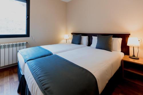 1 dormitorio con 1 cama blanca grande con almohadas azules en Pierre & Vacances La Merceria, en El Tarter