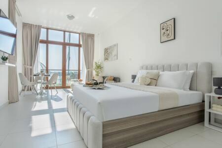 a white bedroom with a large bed and a table at Frank Porter - Palm Views West in Dubai
