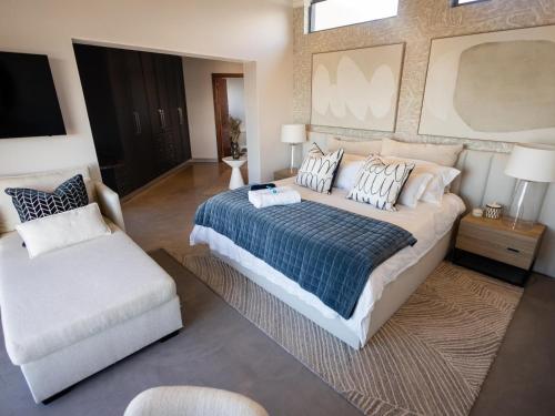 a bedroom with a large bed and a white chair at Yzerfontein Beach Accommodation in Yzerfontein