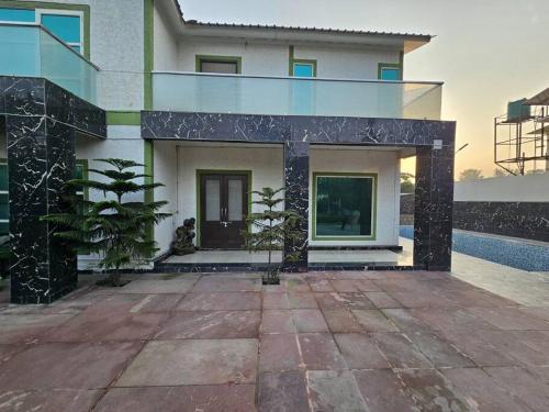 a house with a glass facade with a courtyard at Moksha Farm, 3BHK Luxury Farm Stay, 7000 sq ft in Noida