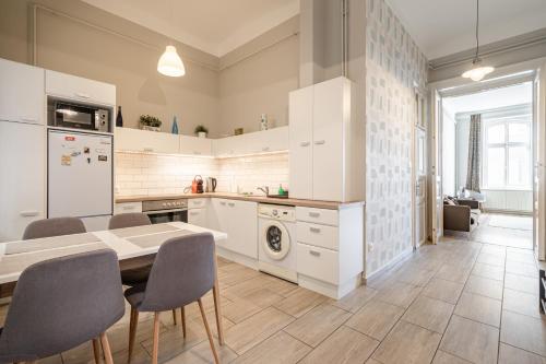 a kitchen with white cabinets and a table and chairs at BpR Castle Hill Apartment with Garden in Budapest