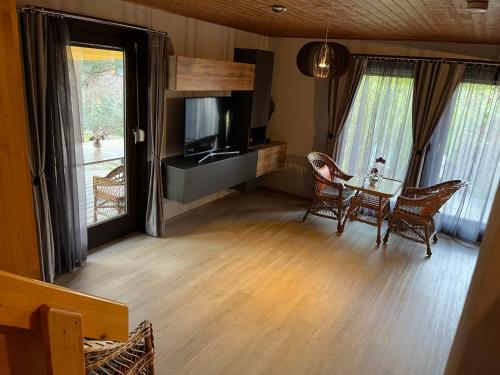 ein Wohnzimmer mit einem Tisch, Stühlen und einem TV in der Unterkunft Ferienhaus 32 in Kinding