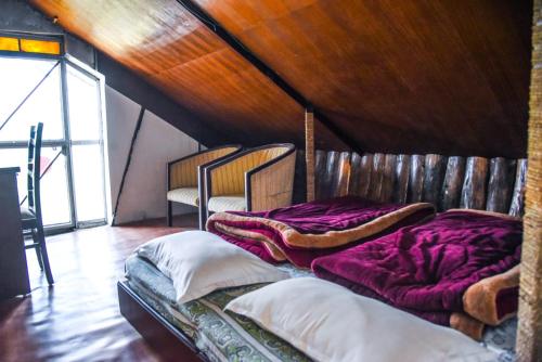 two beds in a room with a wooden ceiling at Dragon I Resorts in McLeod Ganj