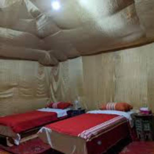 a bedroom with two beds with red pillows at Ibra desert Camp in Merzouga