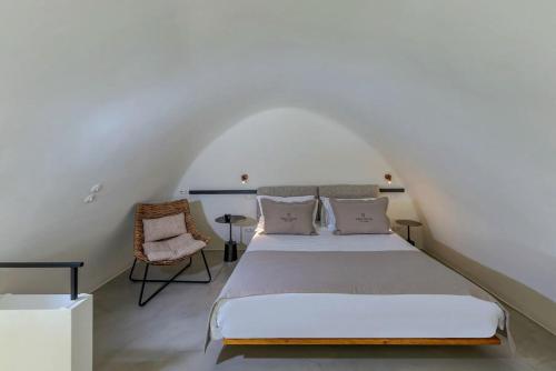 ein Schlafzimmer mit einem Bett und einem Stuhl in der Unterkunft Luxurious Santorini Masionette Villa - 1 Bedroom - Astounding Caldera Sea Views and Private Outdoor Hot Tub - Fira in Fira