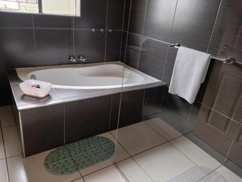 SERENE Guest House في ميدراند: حمام مع حوض استحمام ومغسلة