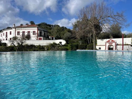 a large pool of blue water in front of a house at Quinta da Asneira in Montemor-o-Novo