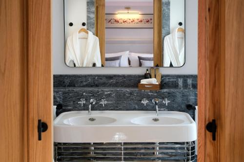 a bathroom with a white sink and two mirrors at Eunice Hotel Gastronómico in Salamanca