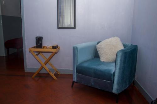 een blauwe stoel met een kussen naast een bijzettafel bij Platina House in Maputo