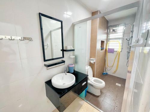 W łazience znajduje się umywalka, toaleta i lustro. w obiekcie Entire 4 BDR white house @ Yong Peng w mieście Yong Peng