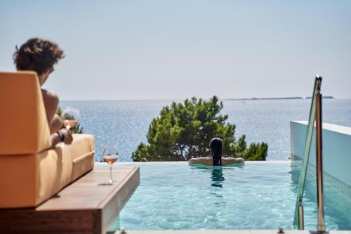 una persona en una piscina con una copa de vino en White Rocks Hotel Kefalonia, en Lassi