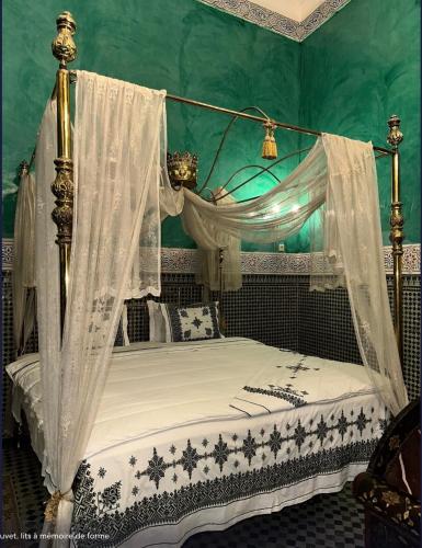 a bedroom with a canopy bed with white curtains at Palais AL Firdaous in Fès
