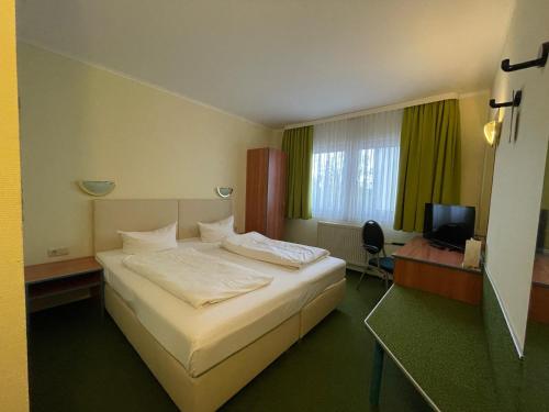 シュクロイディッツにあるREGIOHOTEL Halle Leipzig Airportのベッドとテレビが備わるホテルルームです。