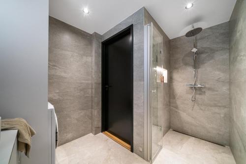 a bathroom with a shower with a black door at Nydelig hytte i unike Lofoten i nærheten av Henningsvær! in Lyngværet
