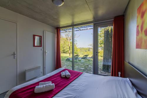 um quarto com uma cama e uma grande janela em Les Collines de Sainte-Féréole em Sainte-Féréole