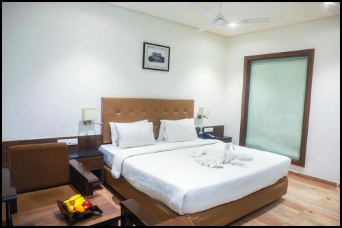 a bedroom with a large white bed and a table at The Byke Suraj Club, Junagadh in Junagadh