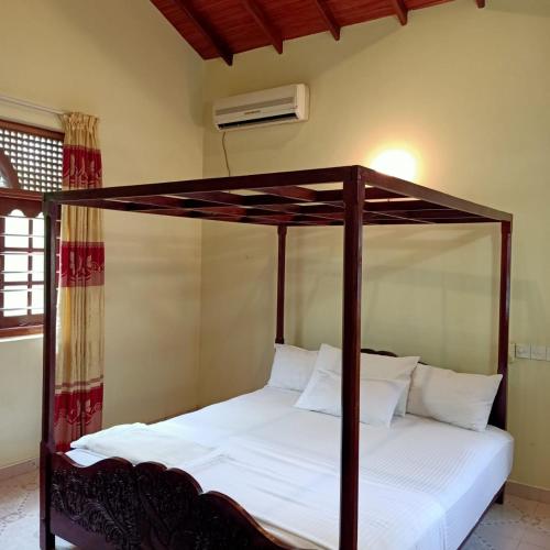 a bedroom with a canopy bed with white sheets at Osh villa in Hikkaduwa