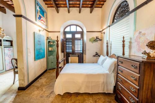 聖胡安的住宿－Charming Retreat in Old San Juan，一间卧室配有一张床、一个梳妆台和一扇窗户。