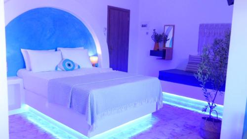a bedroom with a large white bed with a blue headboard at Apartments & Suites Papafotis in Alinda