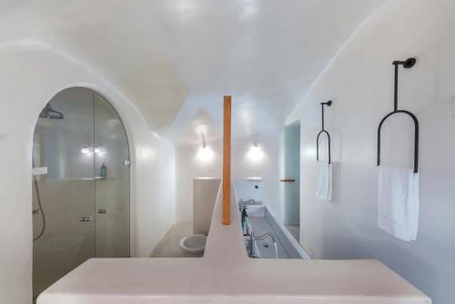 La salle de bains blanche est pourvue d'un lavabo et de toilettes. dans l'établissement Luxury Grand Santorini Villa - 3 Bedrooms - Unforgettable Caldera Sea Views and Outdoor Hot Tub - Fira, à Fira