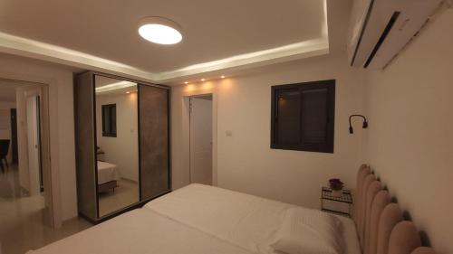 ein kleines Schlafzimmer mit einem Bett und einem Spiegel in der Unterkunft Y.L אירוח בוטיק in Bet Scheʼan