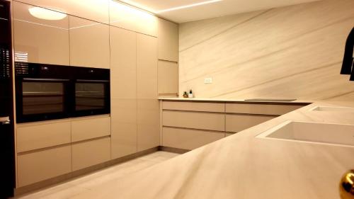 eine weiße Küche mit Spüle und Mikrowelle in der Unterkunft Y.L אירוח בוטיק in Bet Scheʼan