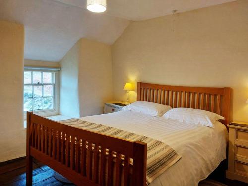 a bedroom with a large bed and a window at Gallestra a Rustic, Rural Retreat Farm House Nr Dolgellau Snowdonia in Dolgellau