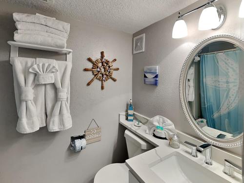 W łazience znajduje się toaleta z umywalką i lustro. w obiekcie Victorian 5302- Oceans Away w mieście Galveston