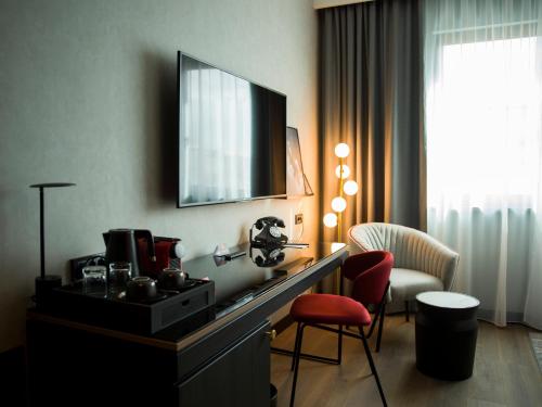 una camera d'albergo con scrivania, TV e sedia di Radisson RED Belgrade a Belgrado