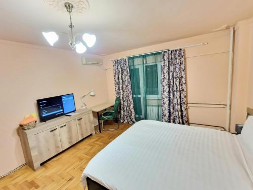 a bedroom with a bed and a flat screen tv at Global Downtown Apartments - Unirii in Bucharest